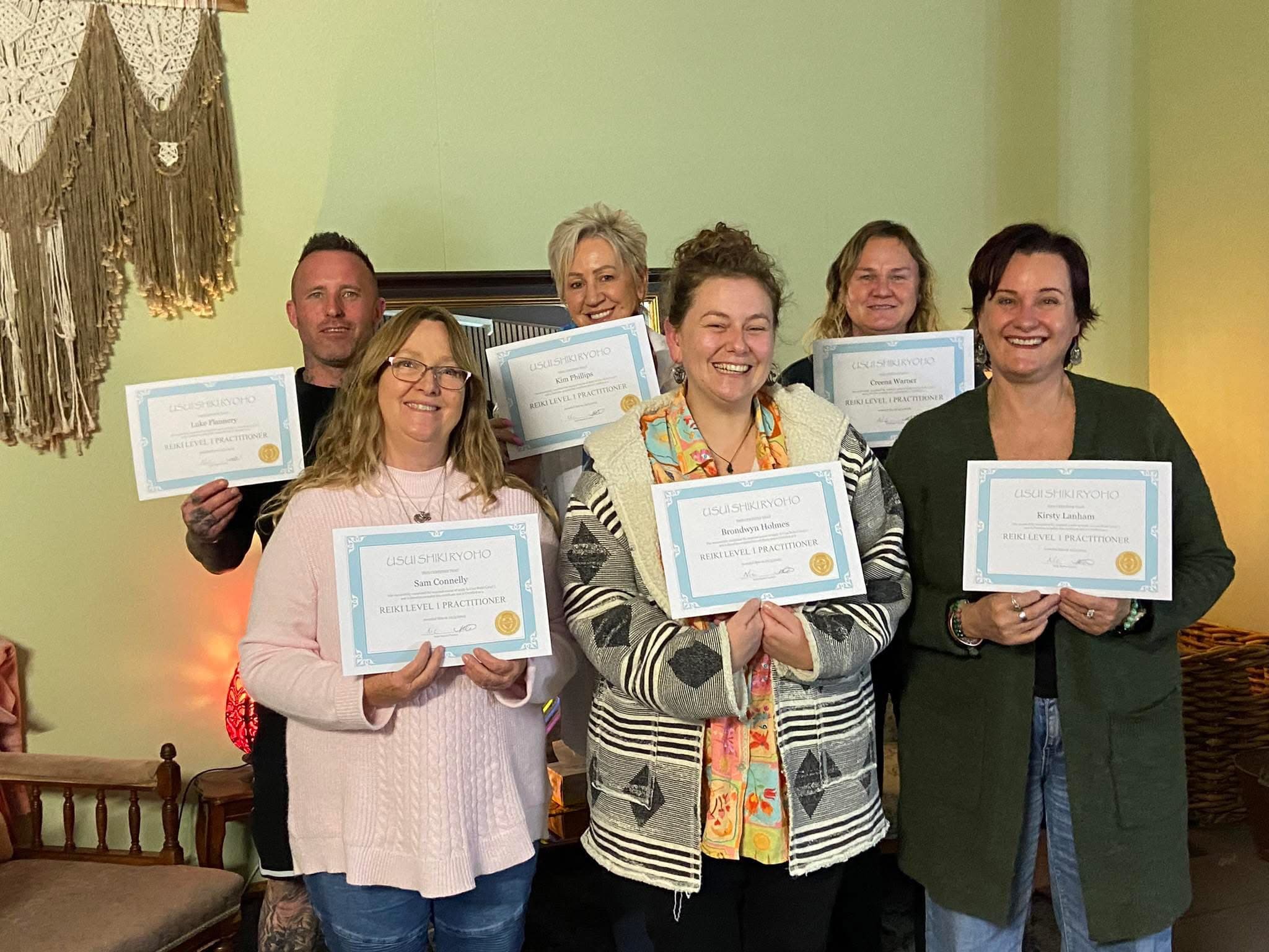 Reiki Level 1 graduates holding their practitioner certificates